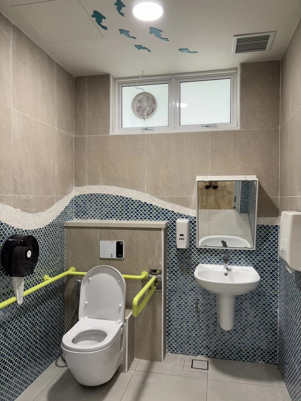 Accessible washroom with marine-patterned wall tiles at NTUC Health Bedok