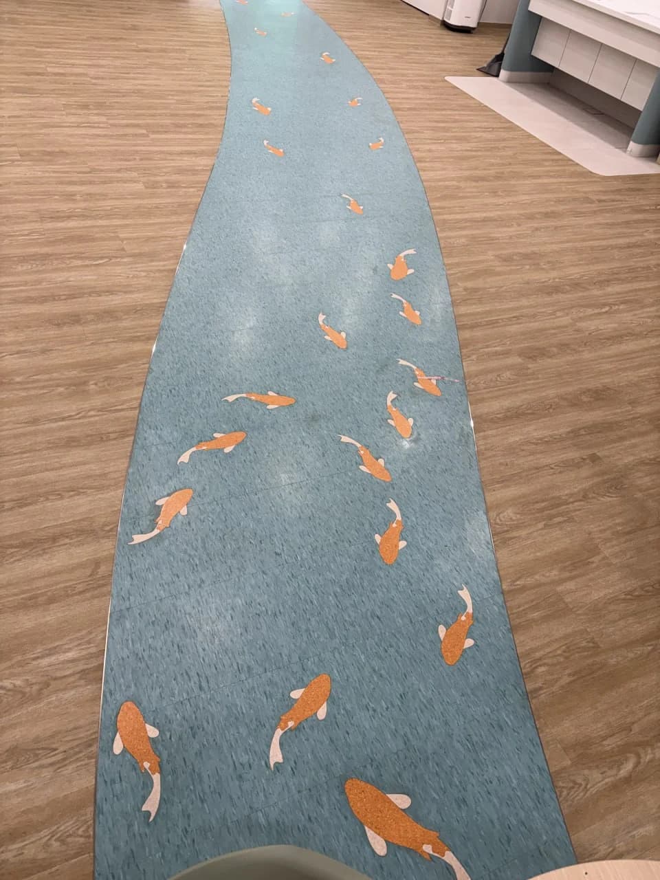 Curving blue floor inlay with orange koi motifs at NTUC Health Bedok