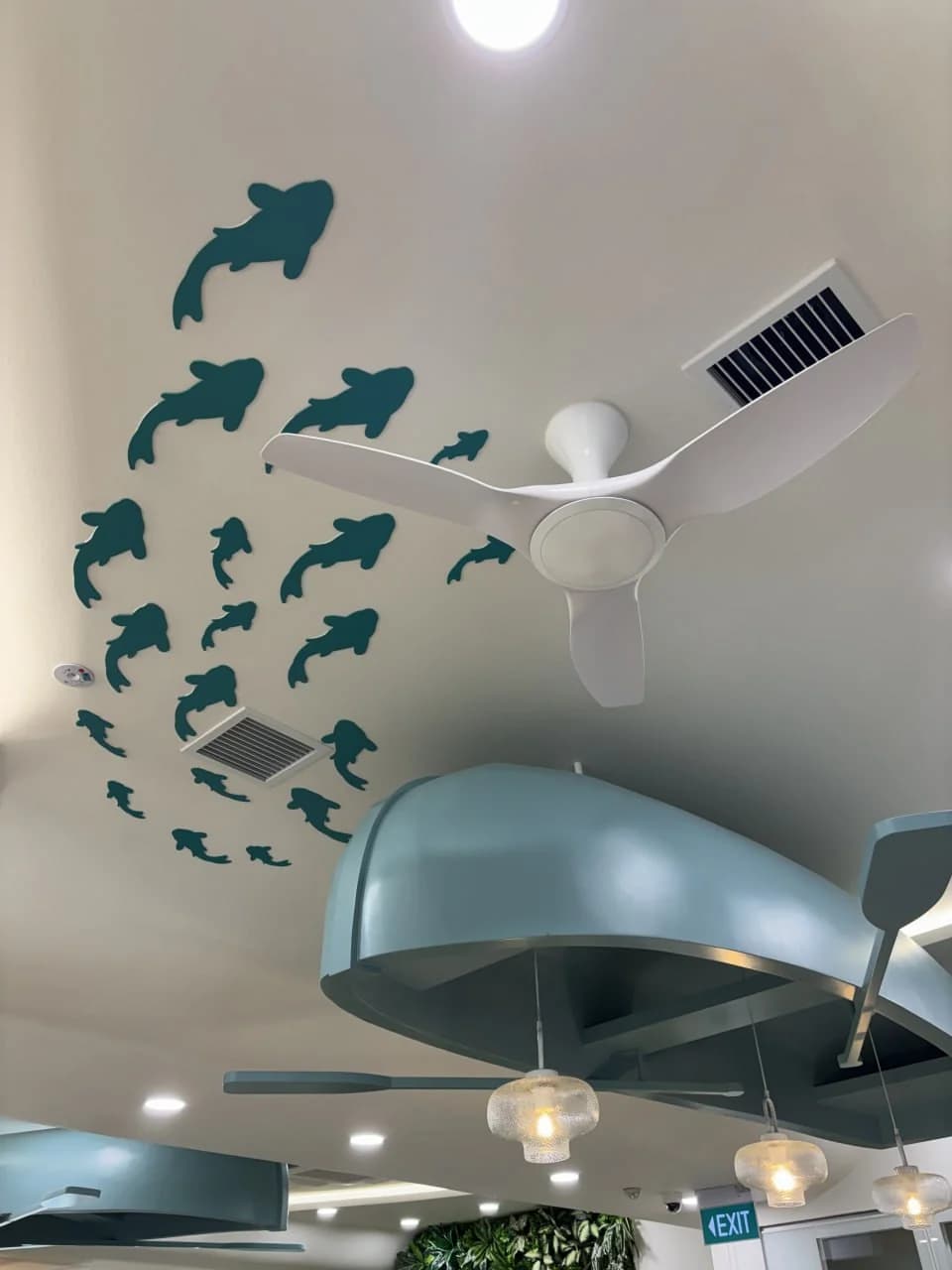 Fish-patterned ceiling and sculptural marine feature at NTUC Health Bedok