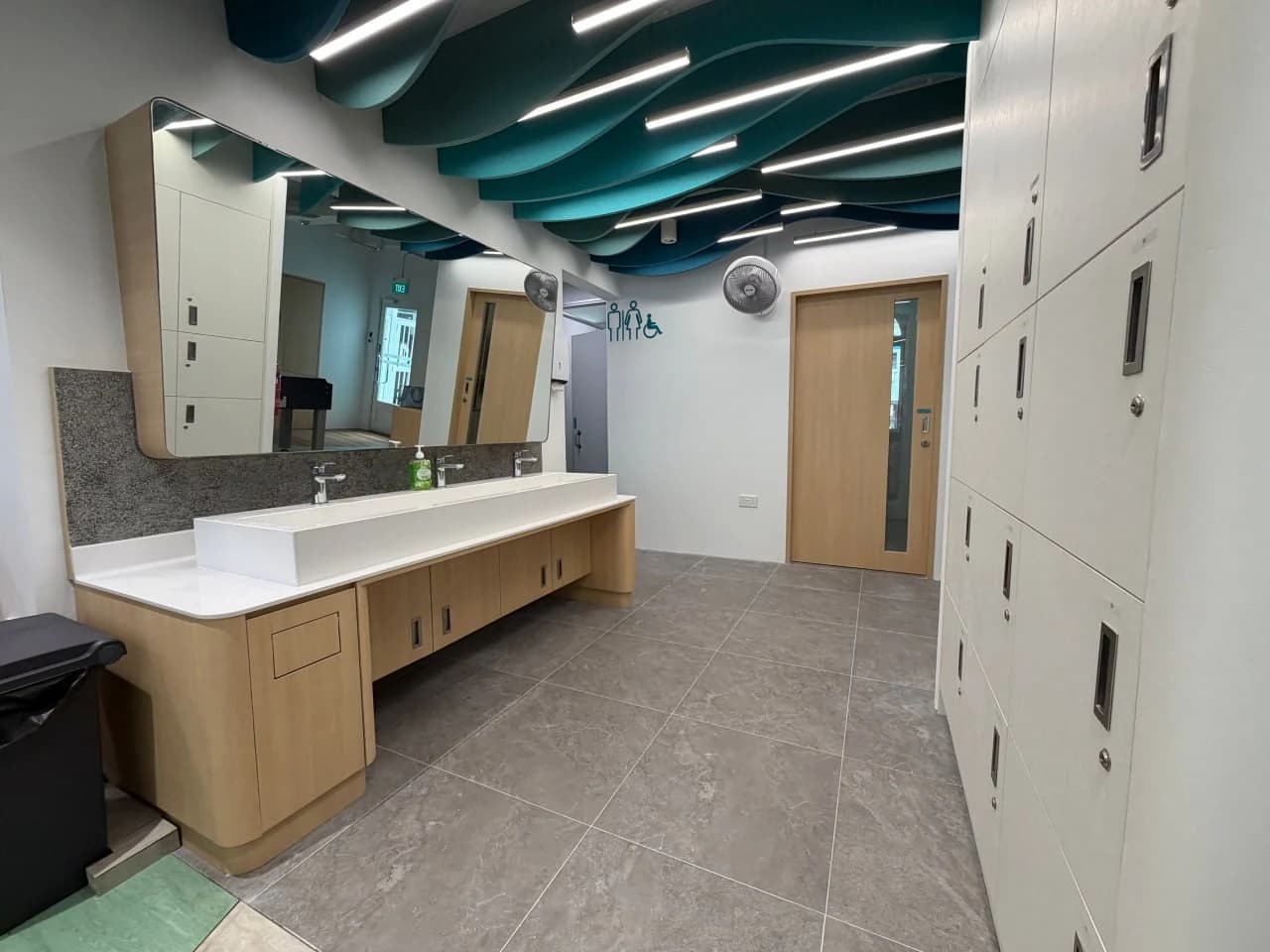 Accessible locker and vanity area with wave acoustic ceiling panels at NTUC Health Marsiling