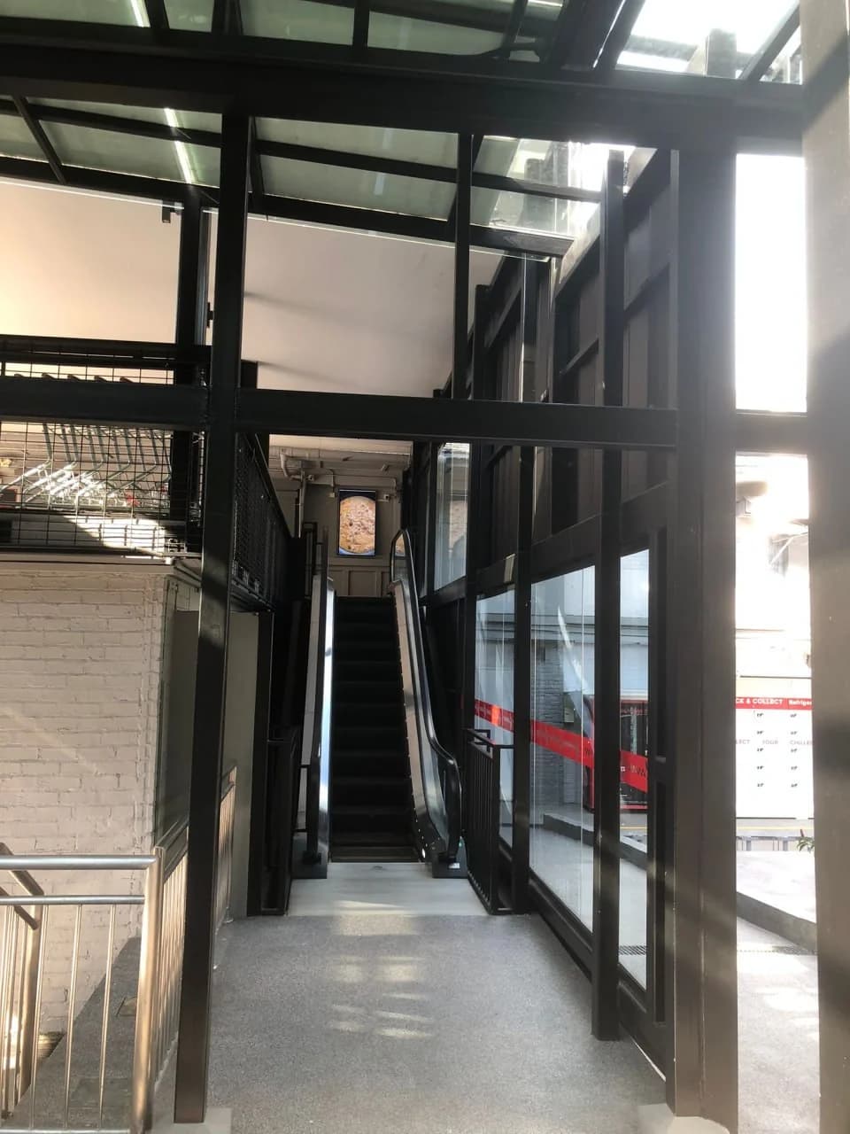 Glazed escalator connection framed by black steelwork at Huber’s Butchery