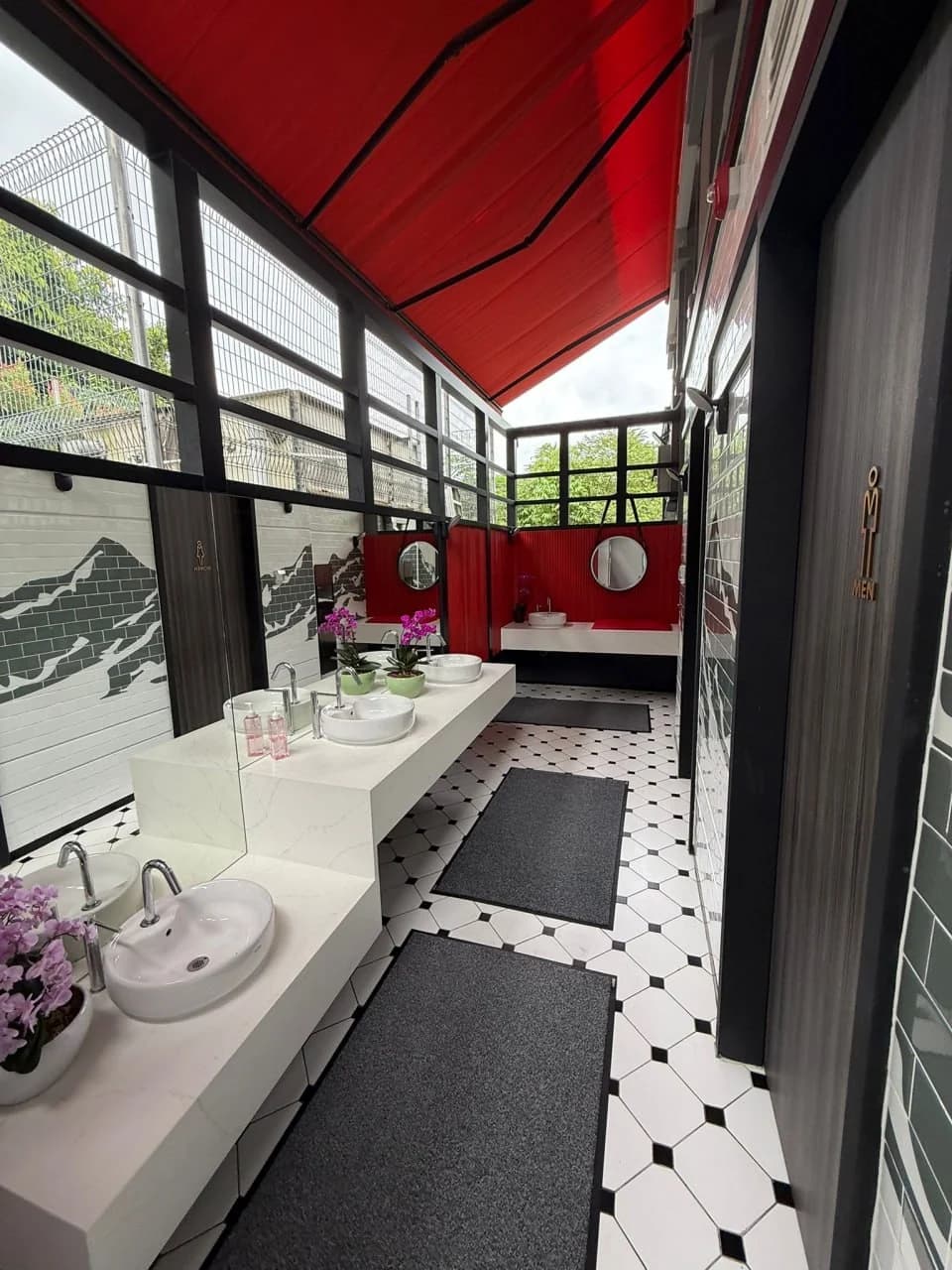 Open-air washroom with red canopy and monochrome finishes at Huber’s Butchery