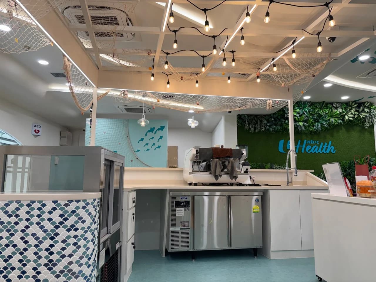 Community café counter with fishing-net ceiling feature at NTUC Health Bedok